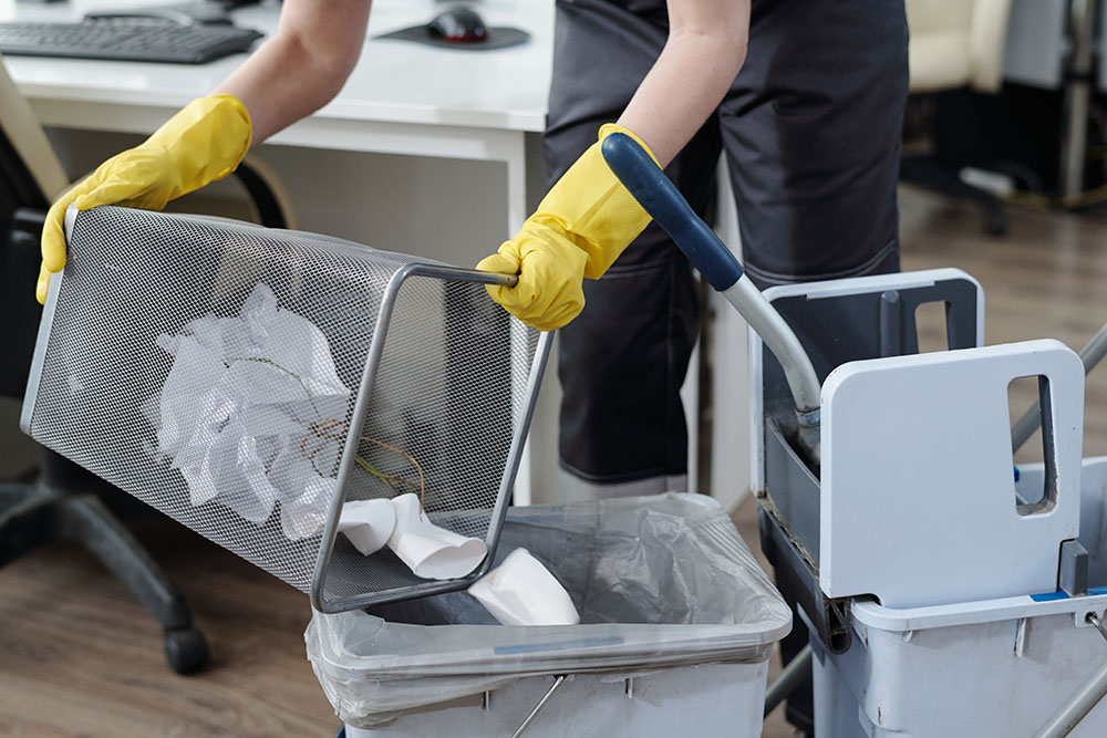 janitor empties waste bin at a city hall